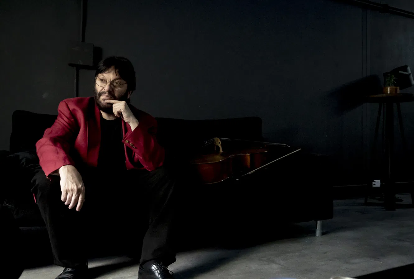 Patricio Villarejo sentado junto a su violonchelo, mirando de costado